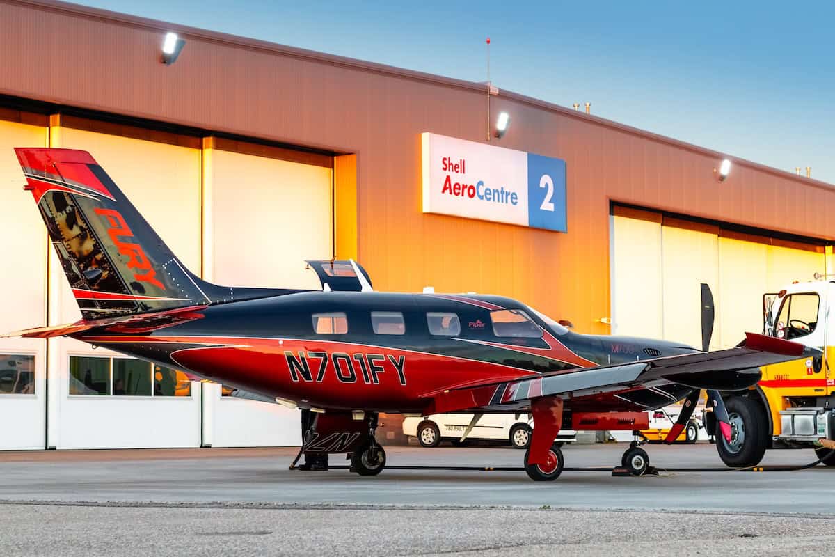 Small airplane outside hangar at sunset.