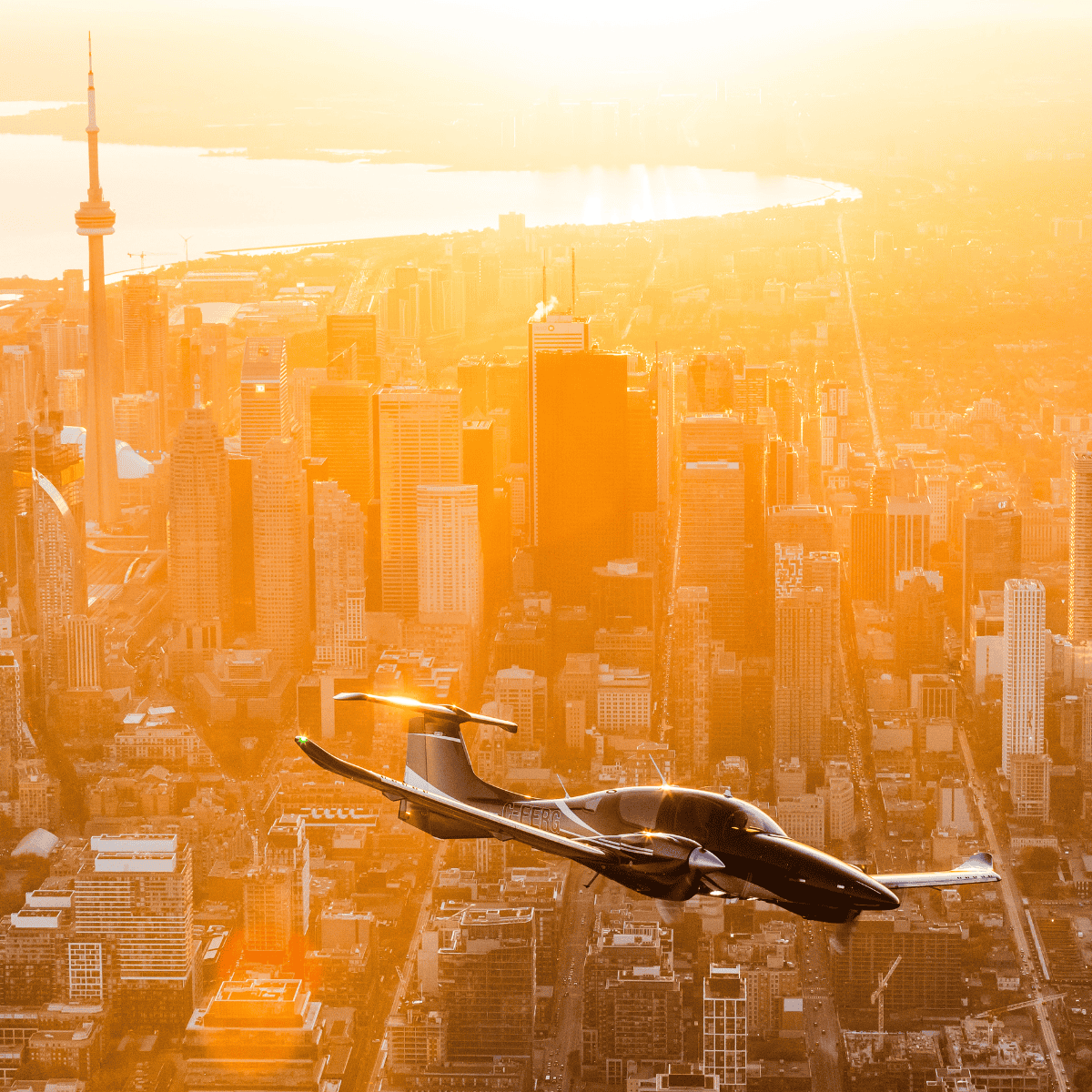 Airplane flying over city skyline at sunset.