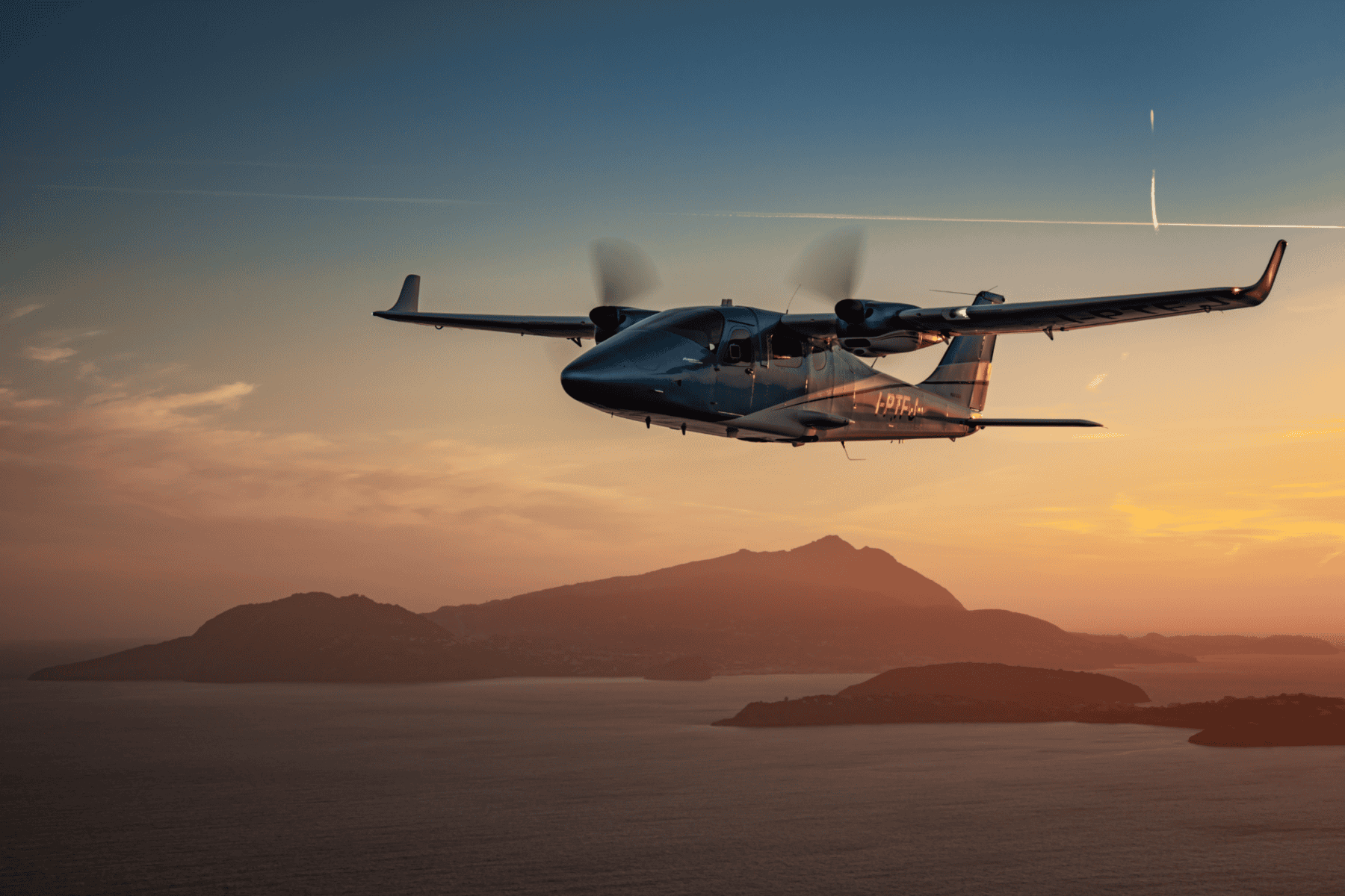 Airplane flying over ocean at sunset