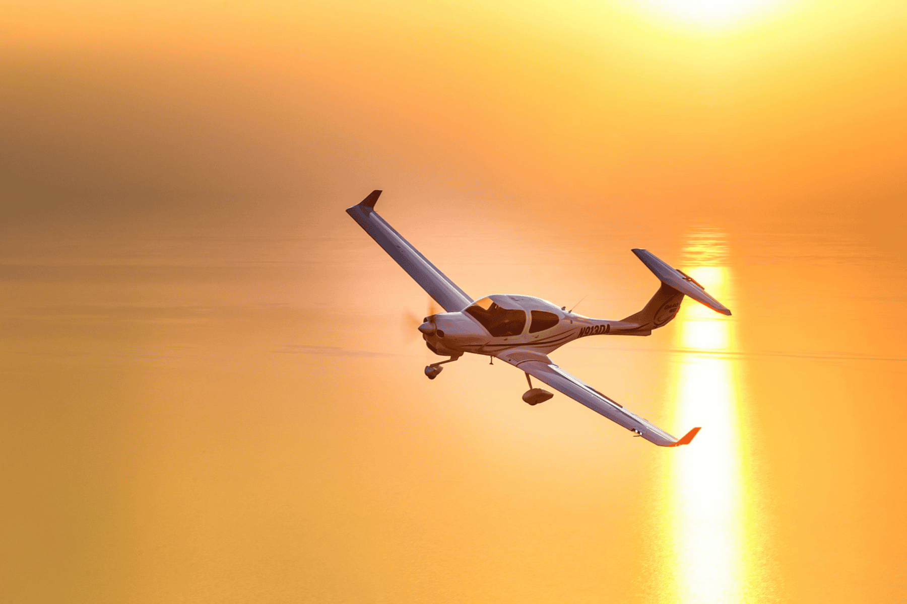 Small airplane flying at sunset over ocean