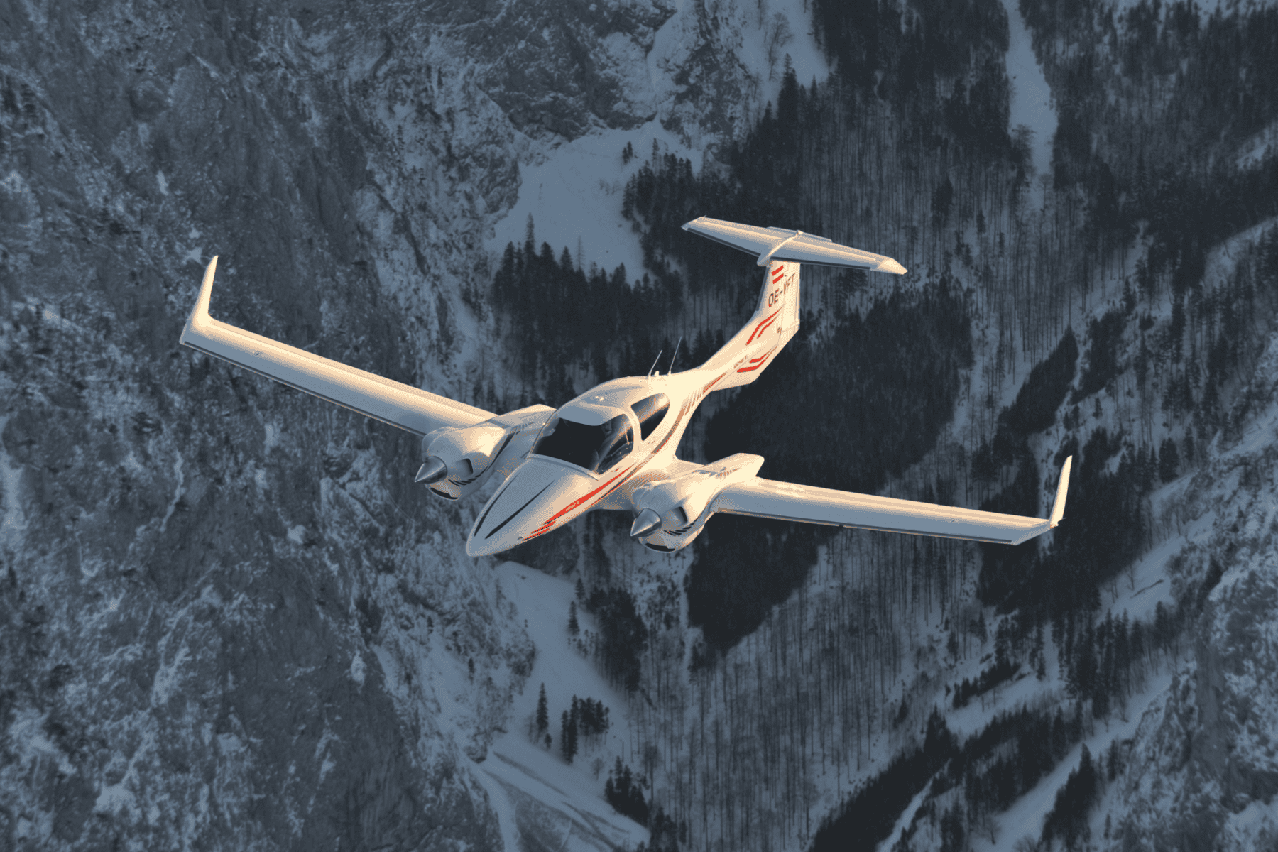 Twin-engine airplane flying over snowy mountains