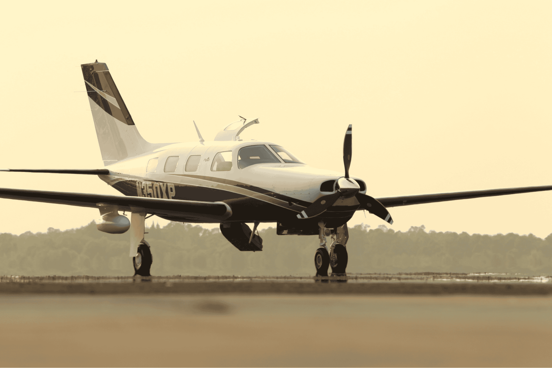 Small propeller airplane on runway at sunset.