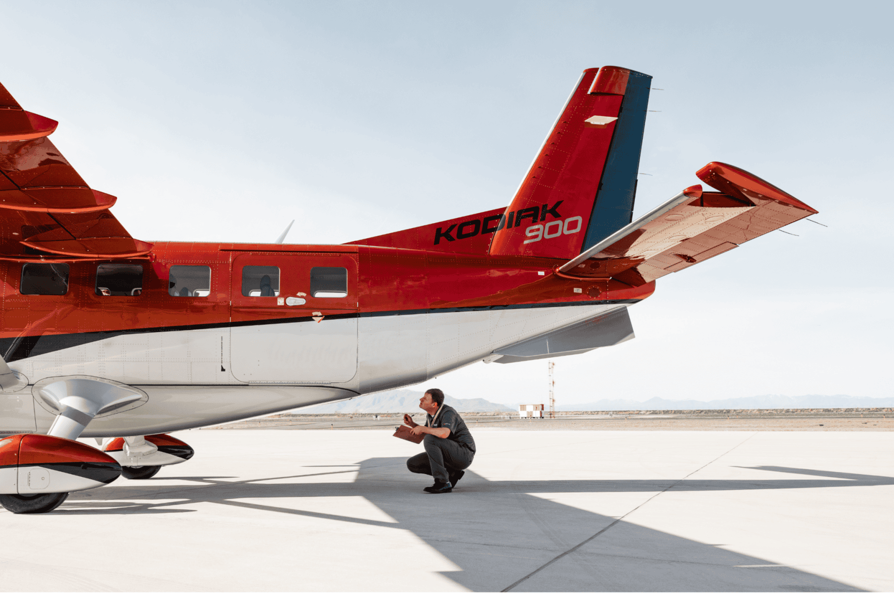 Engineer inspects Kodiak 900 aircraft on tarmac.