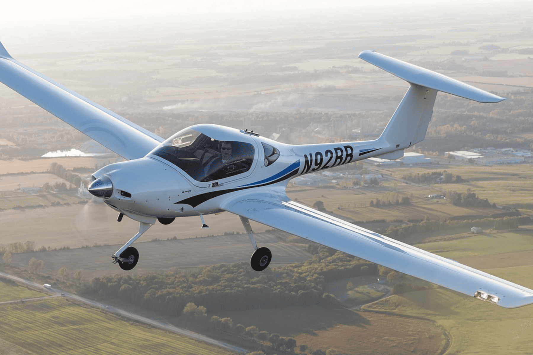 Light aircraft flying over open countryside.