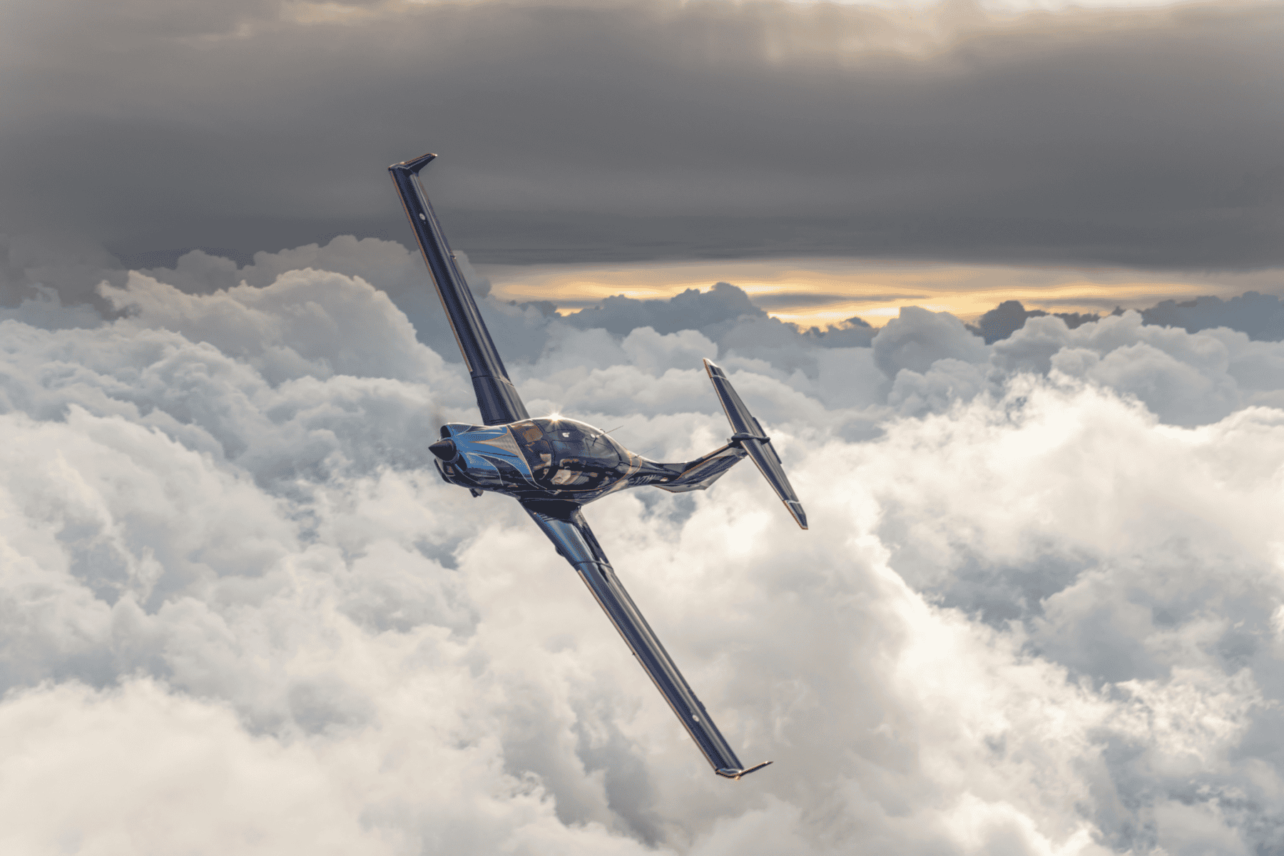Blue airplane flying above the clouds at sunset.