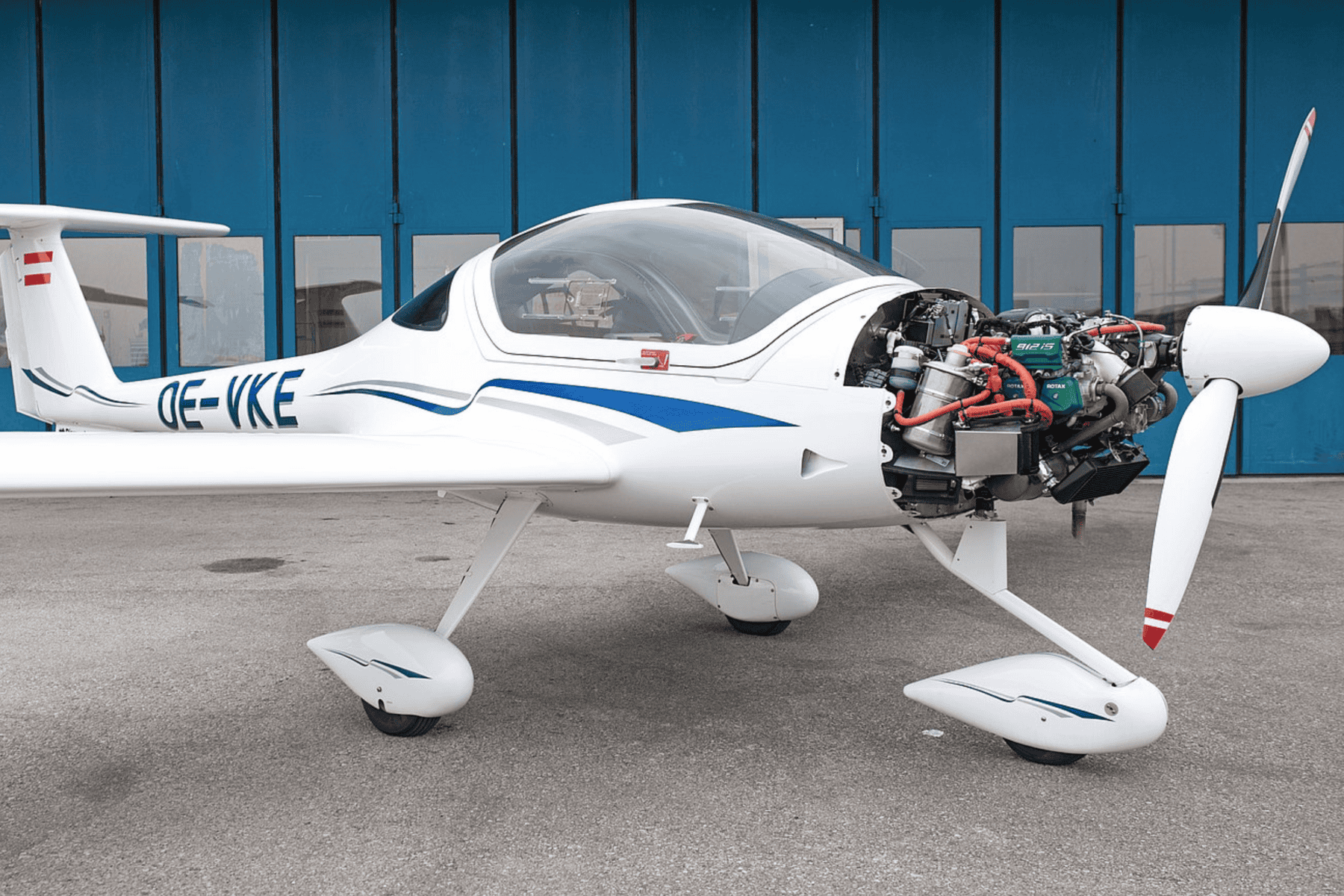 Small airplane with exposed engine on tarmac.