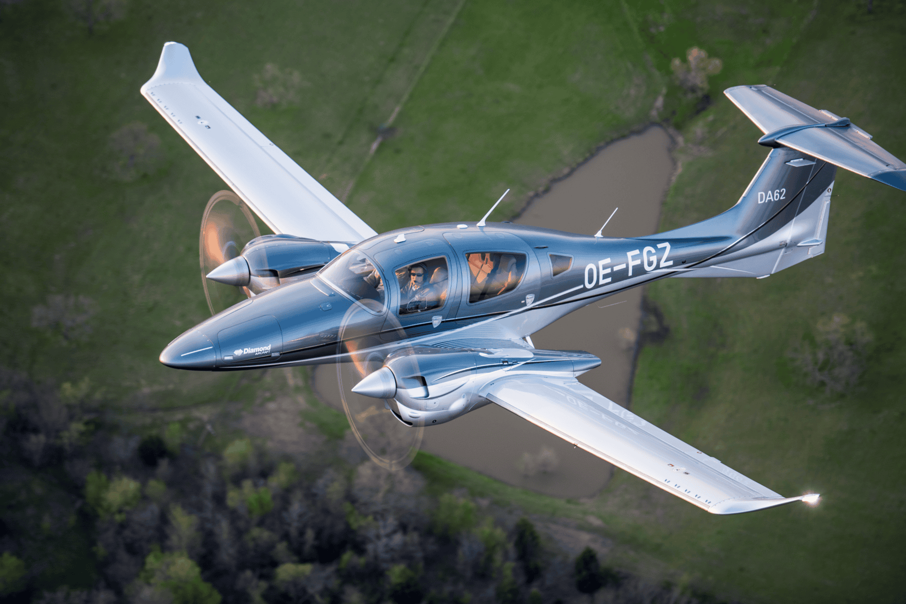 Diamond DA62 aircraft flying over green landscape.